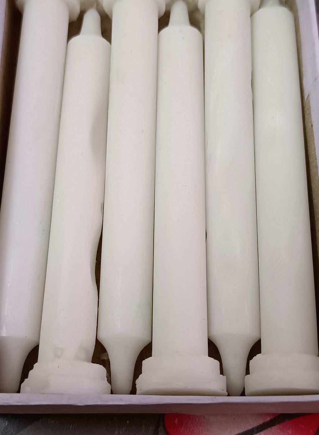 Plain white taper candles formed from candle making wax in Jaipur